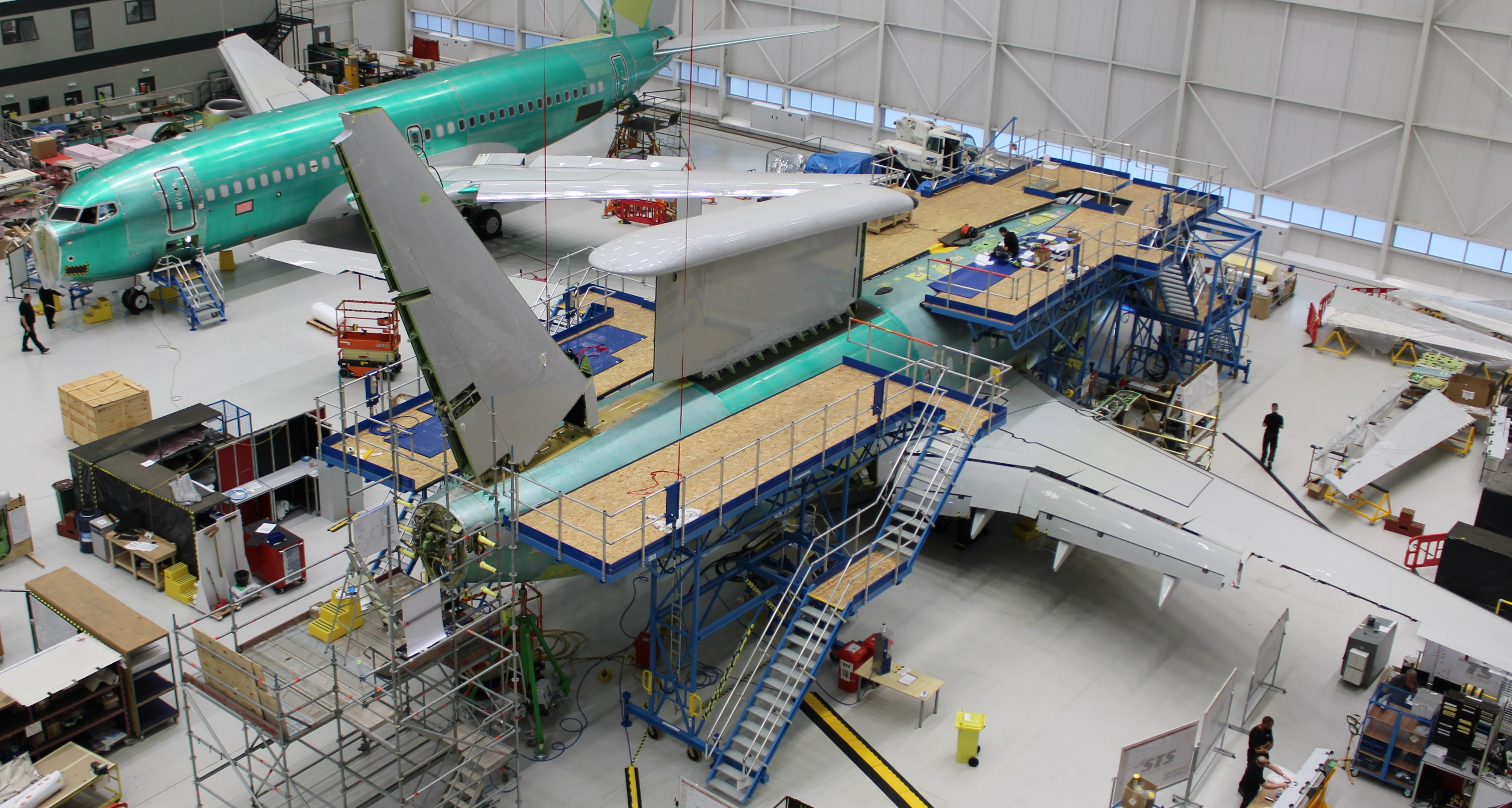 Image shows aircraft parts being assembled inside hangar.